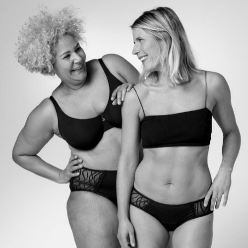 Two women in TENA Silhouette Washable Absorbent Underwear looking at each other smiling